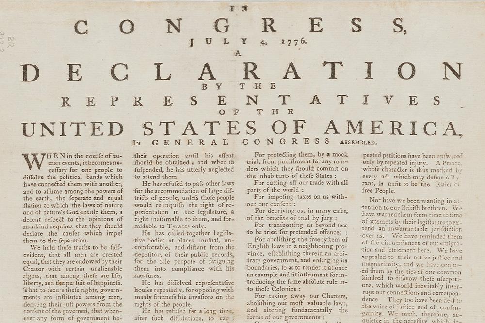 Close-up of the top portion of the United States Declaration of Independence, dated July 4, 1776, showing the heading, introduction, and part of the first paragraph in black printed text on aged paper.