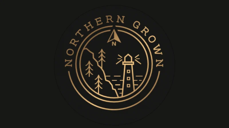 A circular logo with the words "Northern Grown" surrounding line art of a lighthouse, pine trees, a mountain, and a compass needle pointing north, all in gold on a black background.