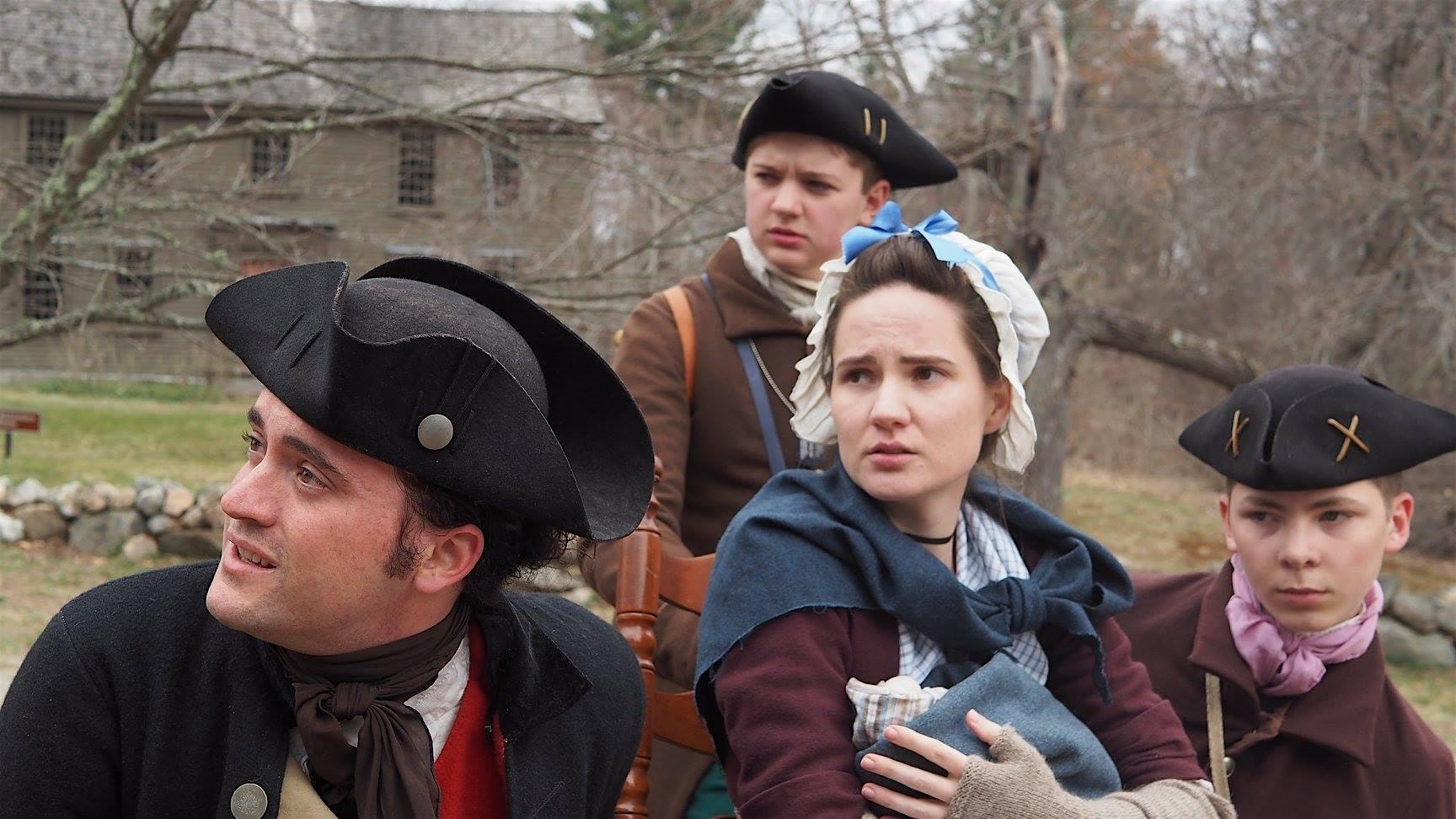 Four people in colonial-era clothing stand outdoors, looking in different directions with serious or concerned expressions. A stone wall, bare trees, and a wooden building are visible in the background.
