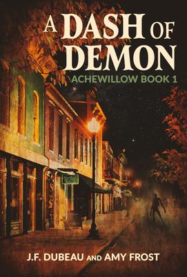 Book cover for "A Dash of Demon: Achewood Book 1" by J.F. Dubeau and Amy Frost, featuring a dimly lit street at night with old buildings, a streetlamp, and a distant shadowy figure.