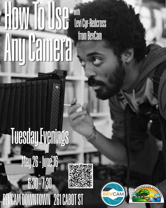 A person looks closely at a camera on a tripod. Text on the image advertises a workshop called "How To Use Any Camera" with Levi Cyr-Relcross, held Tuesday evenings from May 26 to June 16 at 261 Cabot St.