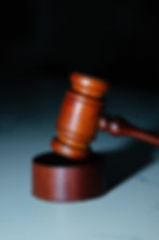 A wooden judge’s gavel rests on a matching sound block against a dark background. The image is out of focus, making the details blurred.