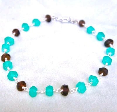 A bracelet with alternating turquoise and brown faceted beads, linked together with silver wire, displayed on a light background.