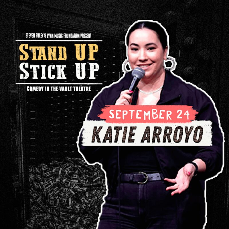 A woman holds a microphone and smiles on stage. Text reads: "Stand Up Stick Up—Comedy in the Vault Theatre. September 24. Katie Arroyo." Money bags are seen in the background. Presented by Steven Foley & LVNA Music Foundation.