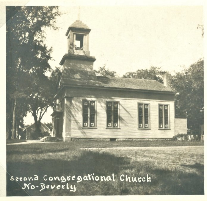 Black and white photo of a small wooden church with tall arched windows and a bell tower. Trees surround the building. Text in the foreground reads, “Second Congregational Church No. Beverly.”.