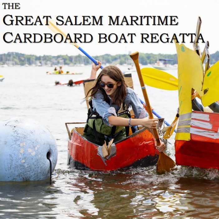 A woman in sunglasses paddles a homemade cardboard boat during the Great Salem Maritime Cardboard Boat Regatta. She appears to be crashing into another cardboard boat with yellow sails on a sunny day. Other boats and people are visible in the background.