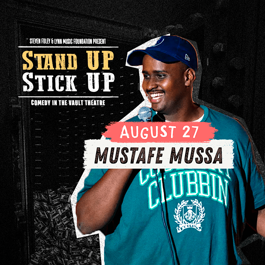 A man in a blue cap and teal shirt holds a microphone on stage. Text reads: "Stand Up Stick Up. Comedy in the Vault Theatre. August 27. Mustafe Mussa." Background shows a dark comedy club setting.