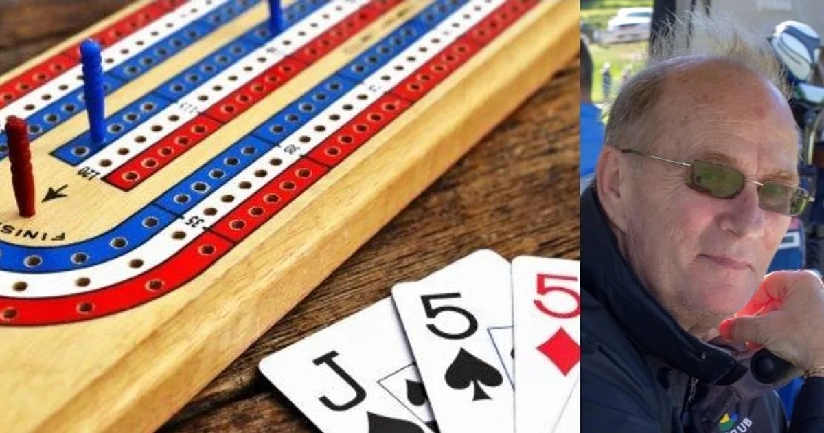 A wooden cribbage board with red, blue, and white pegs is on a table next to playing cards showing two fives and a jack. An older man wearing sunglasses and a jacket sits outdoors on the right side of the image.