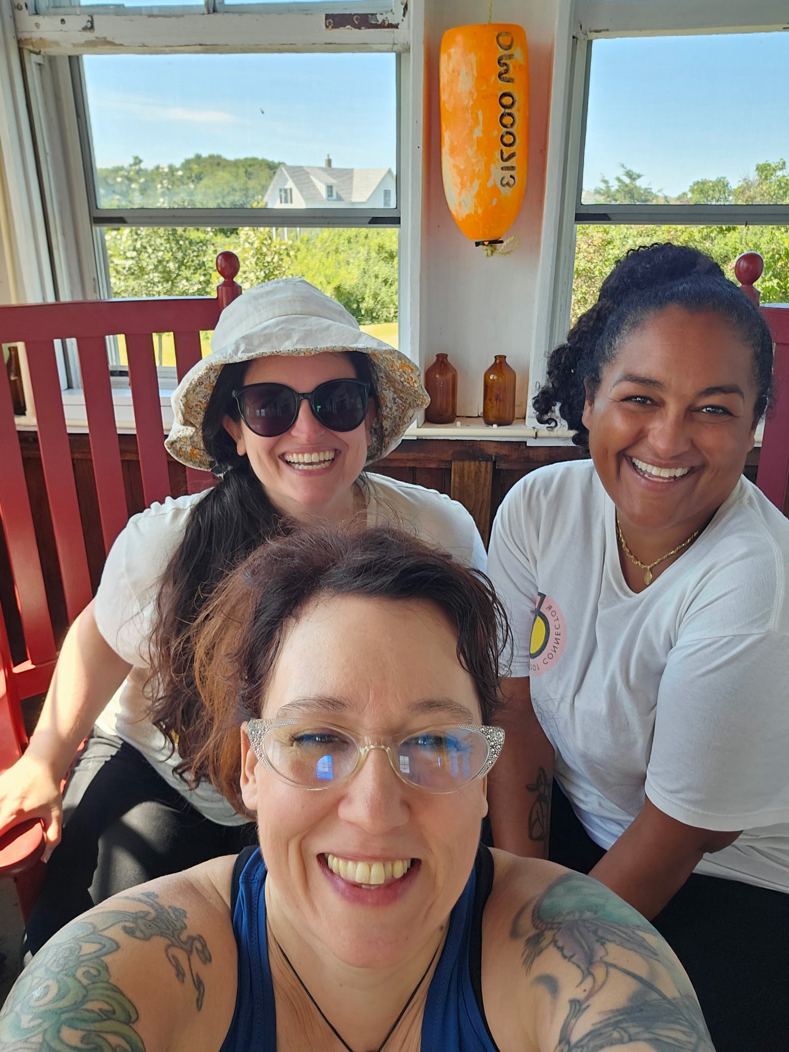 Three Creative Collective members smiling inside the Lightkeepers Cottage during Essex Heritage's Bakers Island volunteer day.