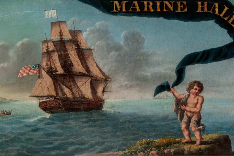 A large sailing ship with an American flag is on the ocean near the shore. In the foreground, a child in a white cloth stands on rocks holding a blue-green ribbon. Part of the words “MARINE HAL...” appear at the top. The sky is partly cloudy.