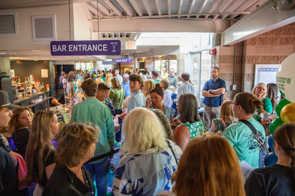 The lobby at North Shore Music Theatre packed with guests in green Patrick's Pack shirts before A Night for Patrick on August 24, 2026