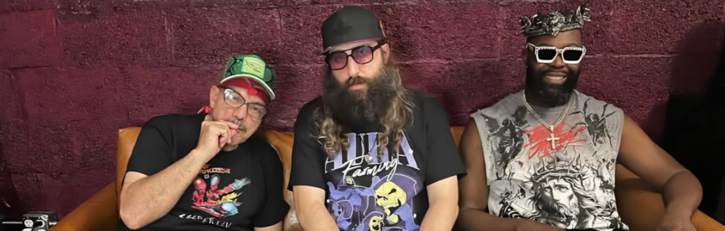 Three men from the funk band Secret Army sit on a brown couch: the left wears glasses and a green cap, center sports a long beard and sunglasses, while Danny Bedrosian, on the right, dons a silver crown, white sunglasses, and chain necklace.