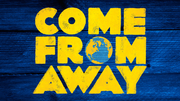 Yellow text reading “COME FROM AWAY” on a textured blue wooden background. The show’s title, Come From Away, features the letter “O” in “FROM” replaced by a globe illustration.