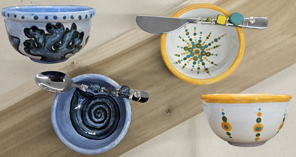 This Charcuterie Accessory Set by EOS Designs features four hand-painted ceramic bowls, each with unique swirls, abstract patterns, and dotted motifs in blue, yellow, and green tones. Each bowl comes with a matching spreader or spoon.