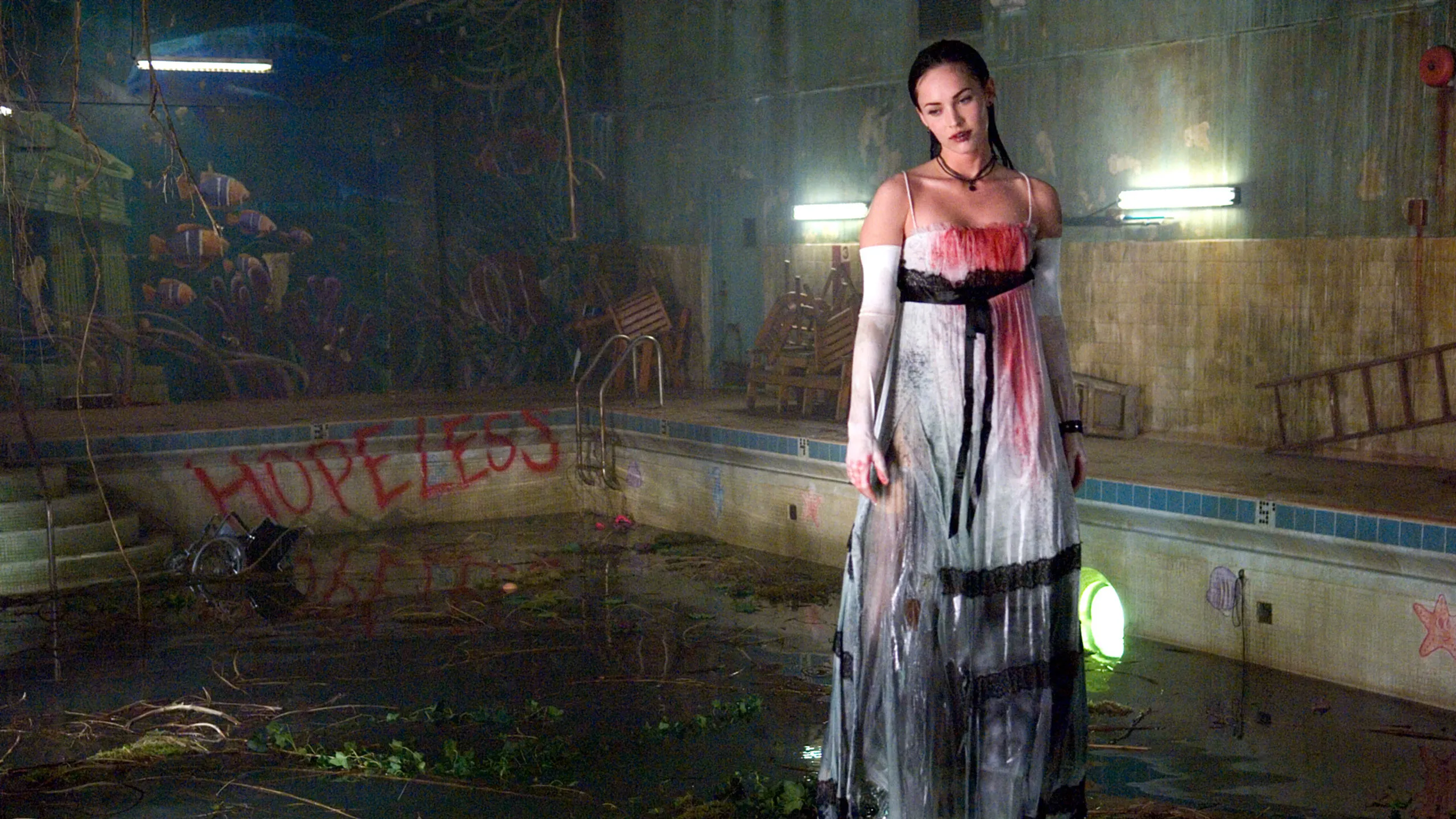 A woman in a white and black dress stands in an abandoned, flooded pool area with plants and debris. The word “HOPELESS” is spray-painted in red on the pool wall. The lighting is dim, with some neon accents and overturned furniture in the background.