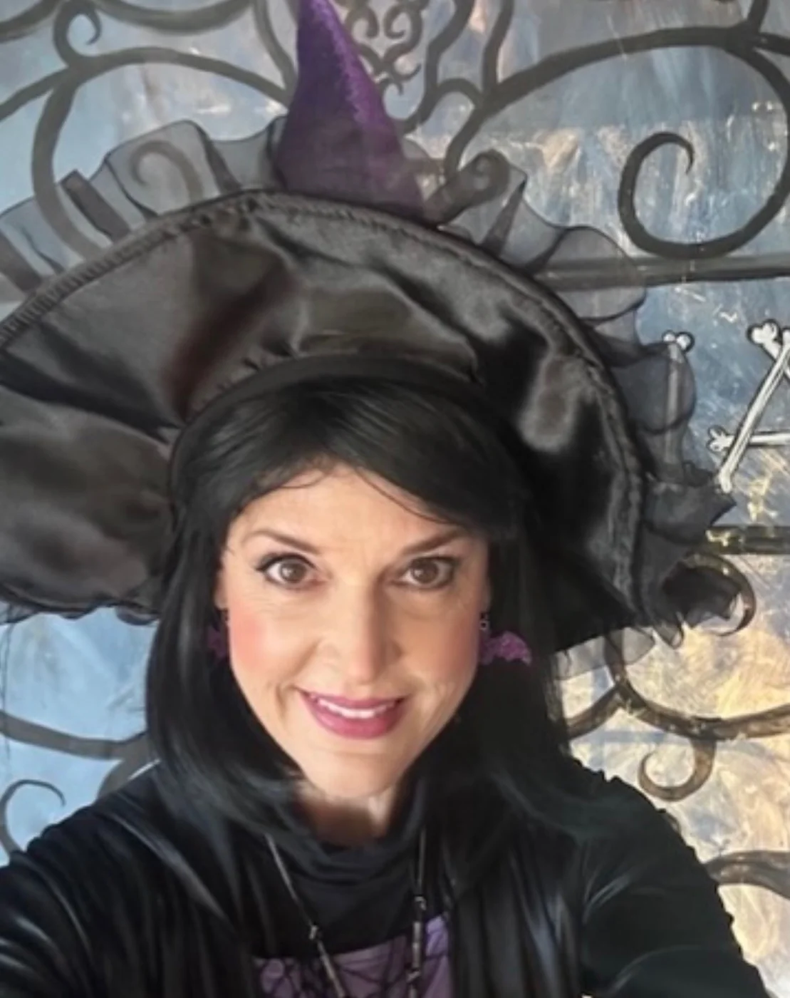 A woman wearing a Halloween witch costume with a black hat and purple accents.