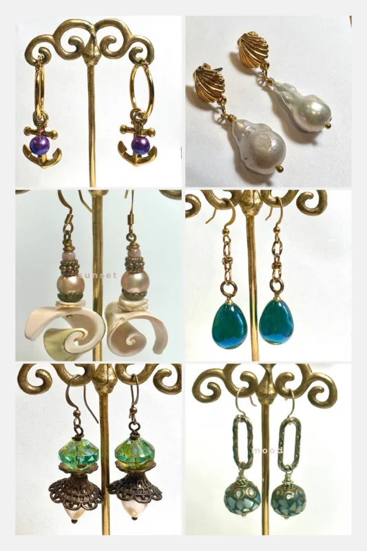 A collage of six pairs of dangling earrings, including anchor-shaped charms, baroque pearls, spiral shells, and colorful beads displayed on gold stands.