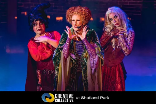 Three performers dressed as the Sanderson sisters from the Rock Cauldron Cabaret perform on a stage, with the text “Creative Collective at Shetland Park” below.