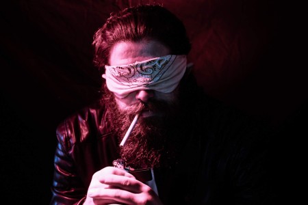 a man with a blindfold smoking a cigarette.
