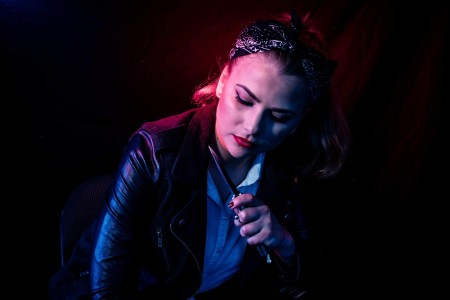 a woman in a black leather jacket smoking a cigarette.