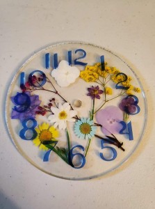 a glass clock with flowers on the face of it.
