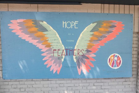 a sign on the side of a building that says hope is a thing of feathers.