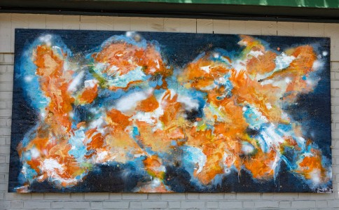 a painting on a brick wall of orange and blue colors.