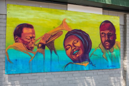 a painting of three people on a brick wall.