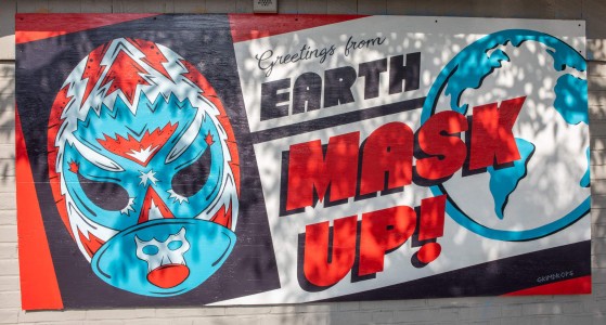 a sign on the side of a building that says earth mask up.