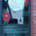 a window with a sign on it that says alone together.