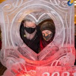 a man and a woman standing inside of a heart shaped ice sculpture.