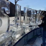 a man standing next to a long row of ice sculptures.
