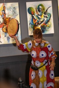 a woman in a colorful dress holding a drum.