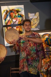 a man holding two drums in front of a painting.