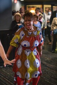 a woman in a colorful dress walking down a hallway.