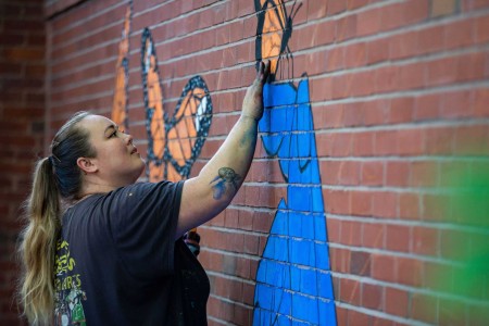 a woman is painting a mural on a brick wall.