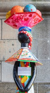 a sculpture of a person holding a colorful umbrella.