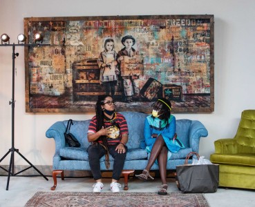 two people sitting on a couch in front of a painting.