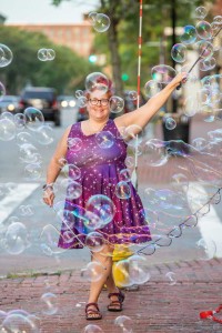 a woman in a purple dress is blowing bubbles.