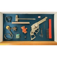 a display case with a gun, a comb, and other items.