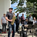 A group of people playing saxophones in front of a group of people.