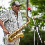 A man with a saxophone standing in front of a microphone.