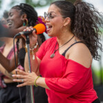 A woman singing into a microphone in front of a group of people.