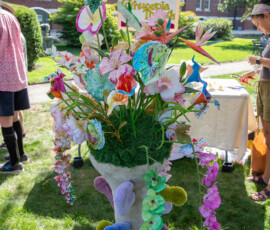 A tall sculptural vase of textile flowers, moss and trailing orchids at the Cornucopia Threads booth on Beverly Common