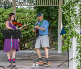 A violinist in a purple dress and a guitarist perform together in the gazebo on Beverly Common at the Beverly Garden Party