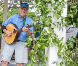 A guitarist sings mid-song in the gazebo on Beverly Common, framed by trailing green vines at the Beverly Garden Party