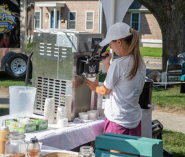 A vendor pulls a soft-serve swirl beside a Sip N Pour fresh squeezed lemonade trailer at Beverly's Garden Party on Beverly Common