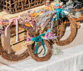 Grapevine wreaths trimmed with dried lavender and velvet ribbons, arranged with air plants on a linen-covered vendor table at the Beverly Garden Party